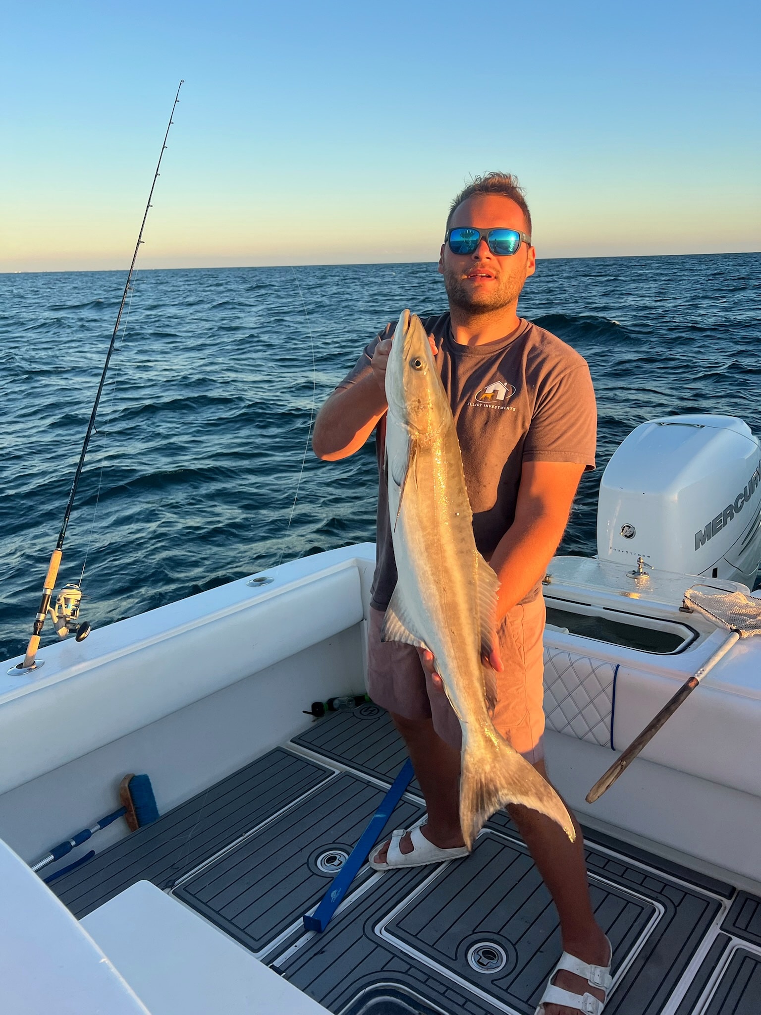 A cobia held up as the sun drops