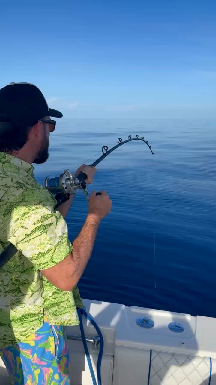 A rod doubled over as an angler fights a fish offshore