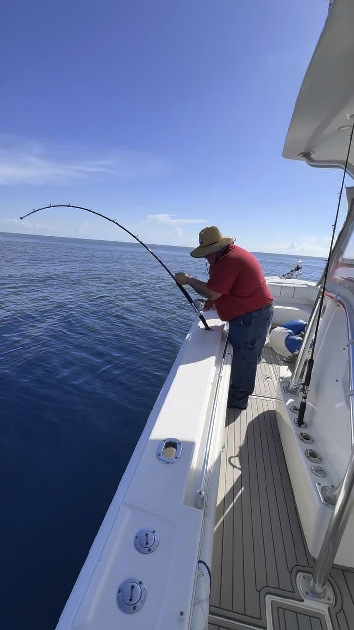 An angler leaning into a fish on flat calm water