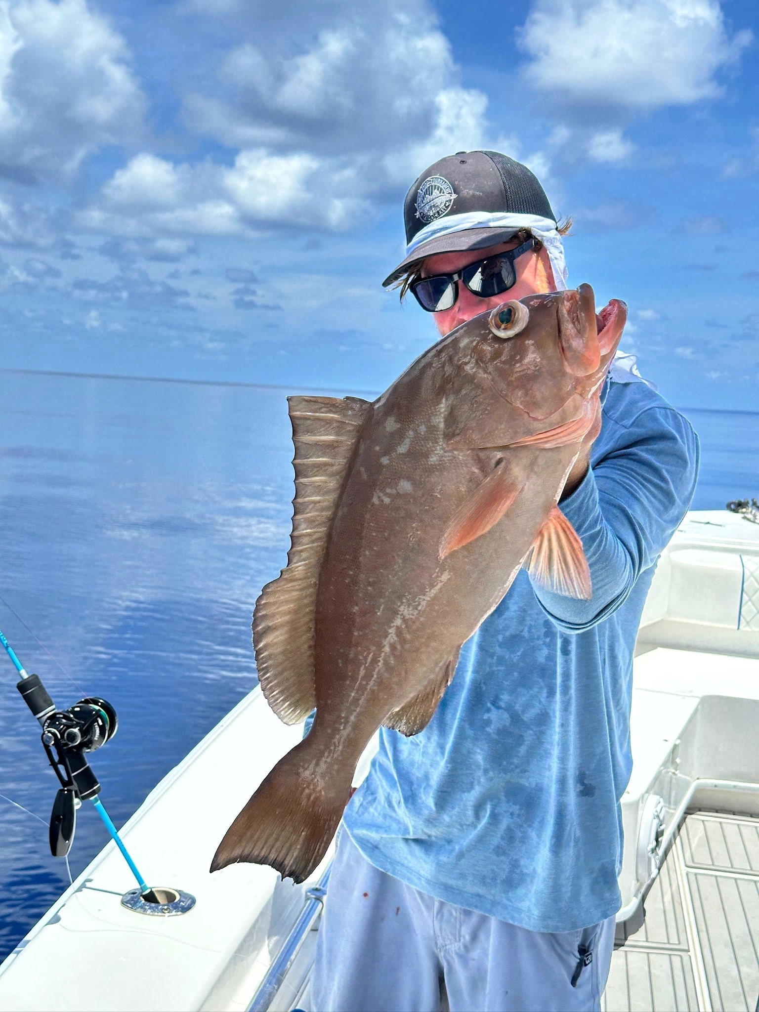 An angler holding a grouper boatside