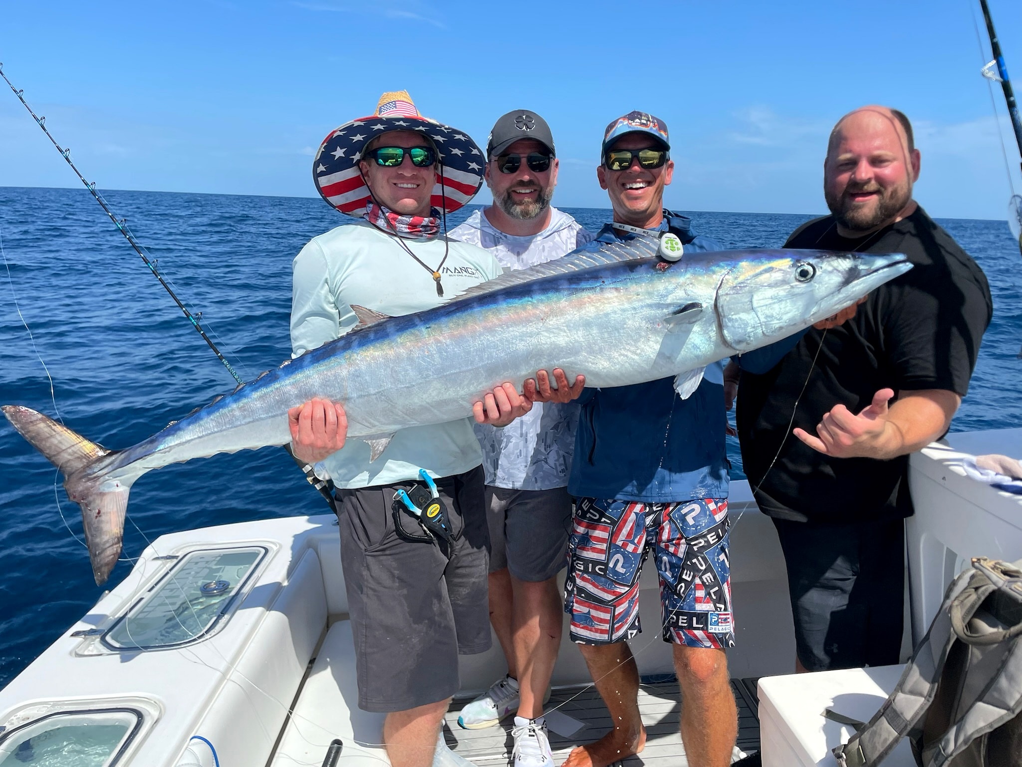 Four anglers with a wahoo across the gunwale after a long-range run
